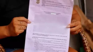 Mulher segurando medida protetiva na mão - (Foto: reprodução)