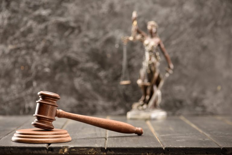 Martelo de juiz e uma estátua da justiça em cima de uma mesa