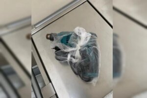Foto colorida mostra delegado Da Cunha de óculos segurando uma arma de fogo enquanto olha para a câmera. Ele é um homem negro, careca e usa uma camisa polo branca.