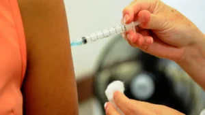 Profissional de saúde aplicando vacina em paciente durante mutirão no Distrito Federal.