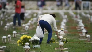 Visitante coloca flores em túmulo durante preparativos para o Dia de Finados no Distrito Federal.